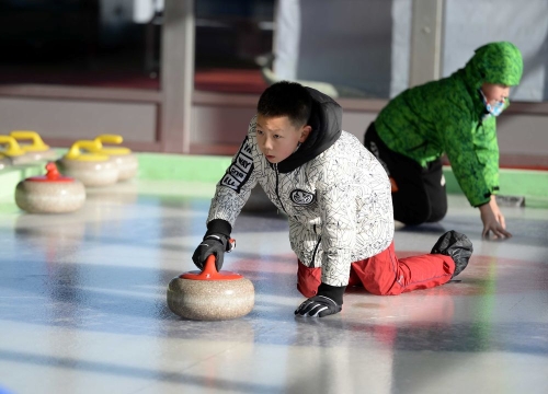 在黑龙江省冬季群众体育活动基地，一名小学生在学习掷冰壶