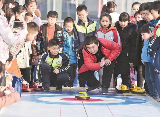 在省首届冰雪运动会上，孩子们体验陆地冰壶。