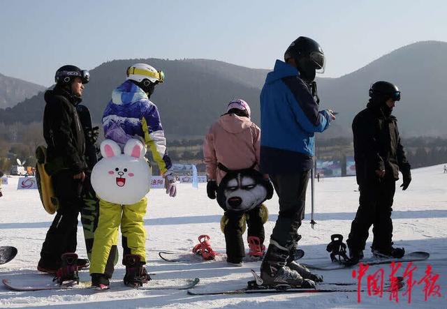 滑雪爱好者保持间隔排队等待坐索道上山
