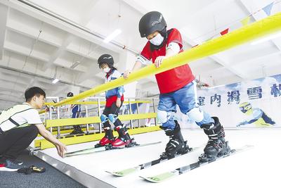 在张家口高新技术产业开发区的冰雪运动培训中心，教练用室内滑雪机对小学生进行培训
